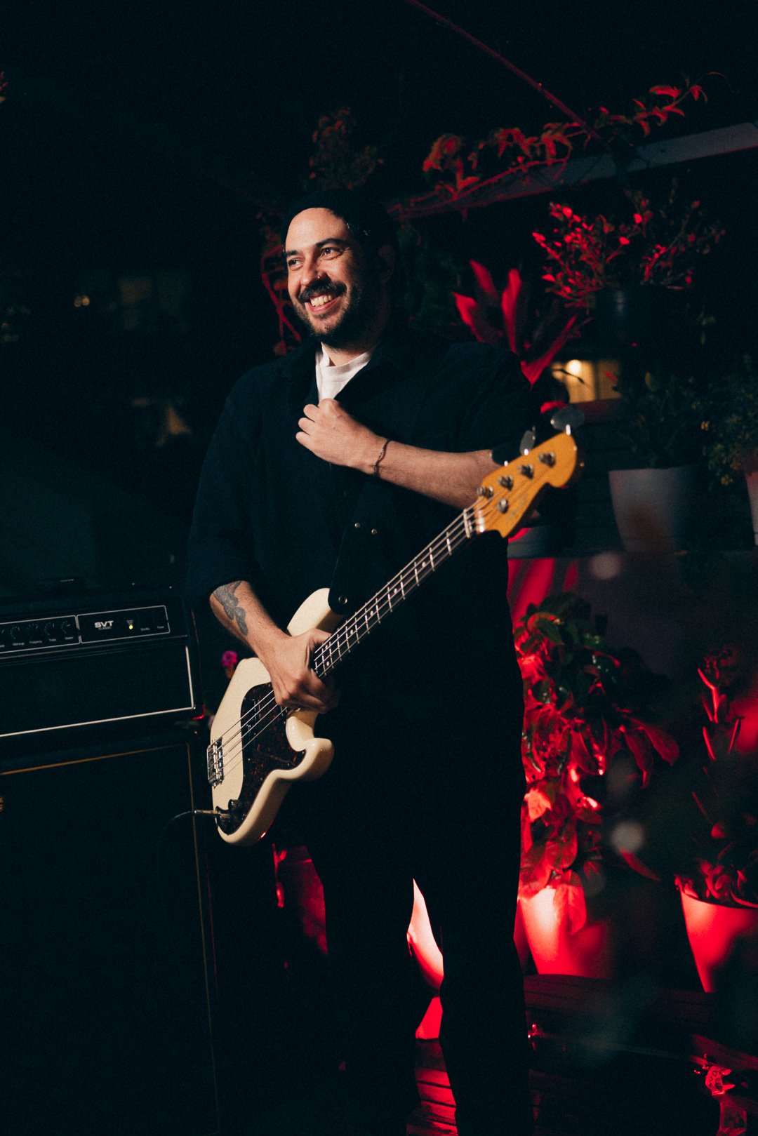 Bassist smiling between songs holding bass guitar on rooftop stage.