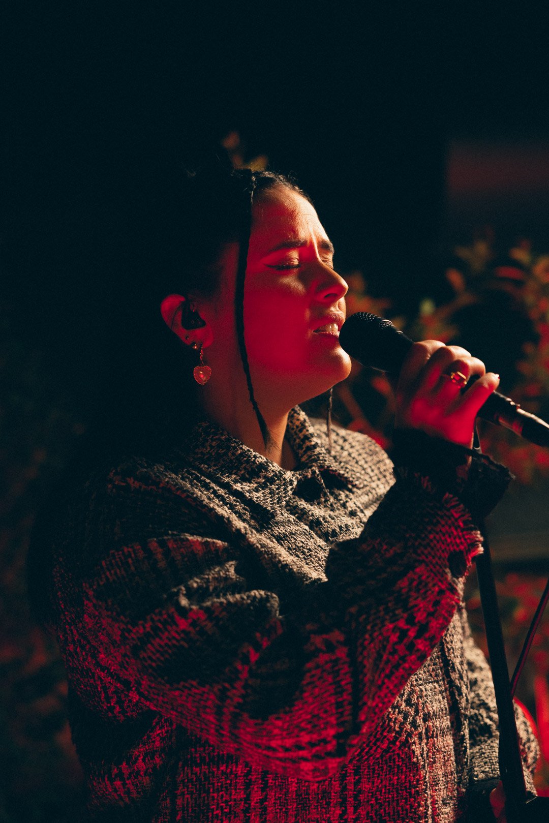 Tia Gostelow singing with eyes closed, immersed in performance.