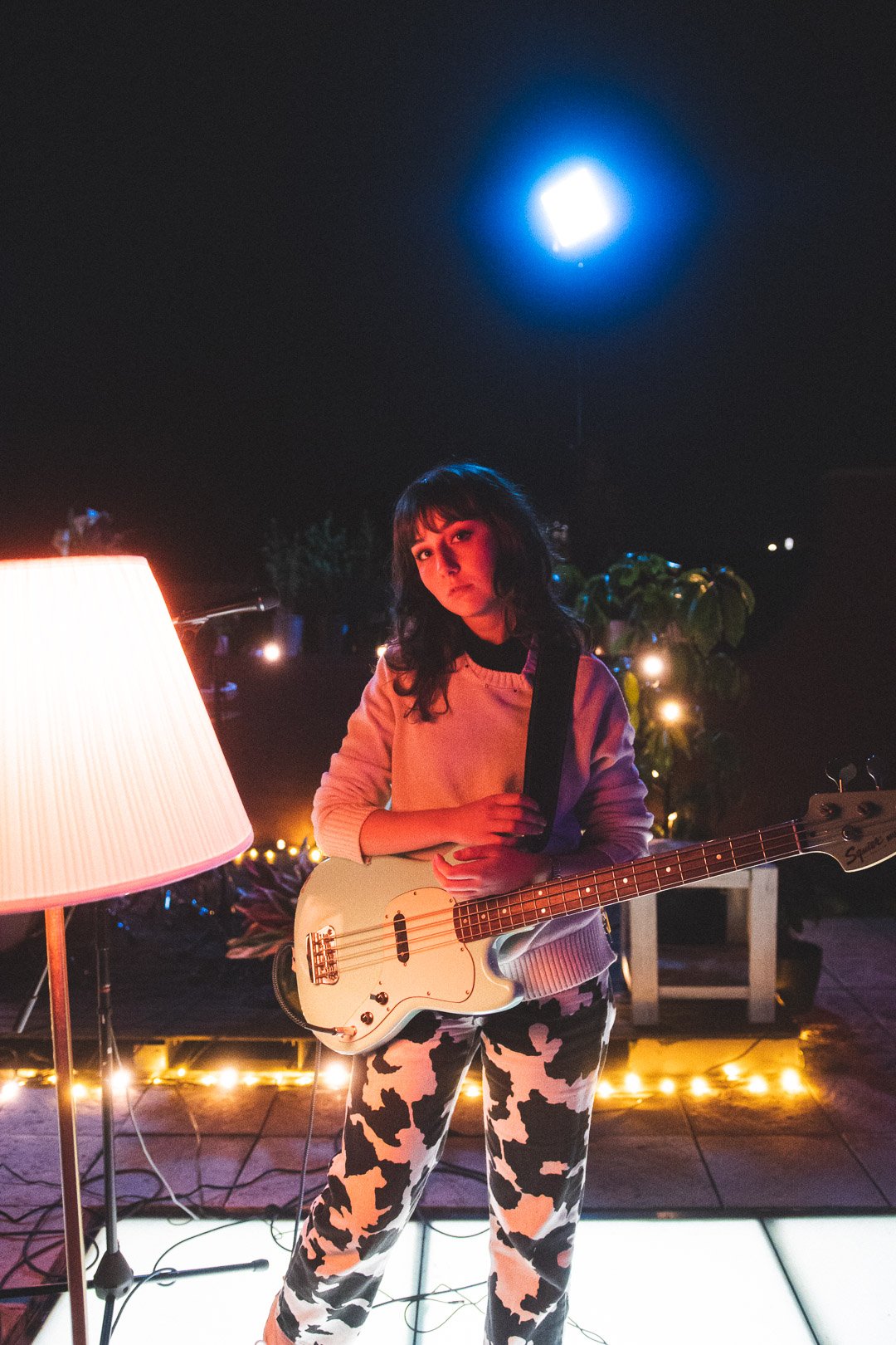 Scout Eastment of EGOISM standing under rooftop lights holding bass guitar.