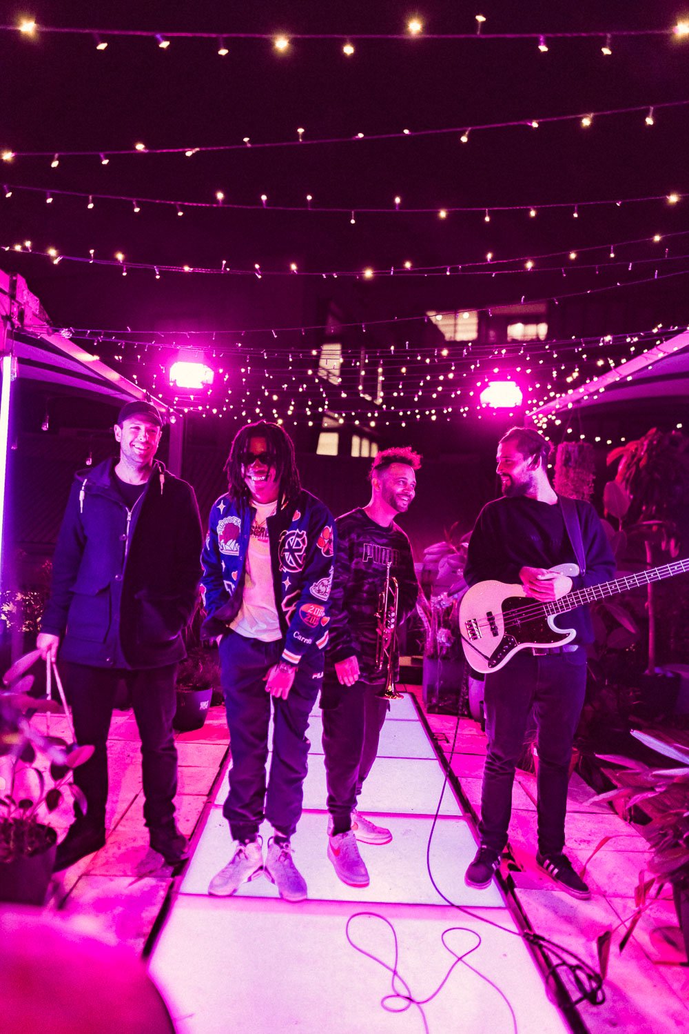 Gold Fang standing with his live band under string lights on the rooftop stage.