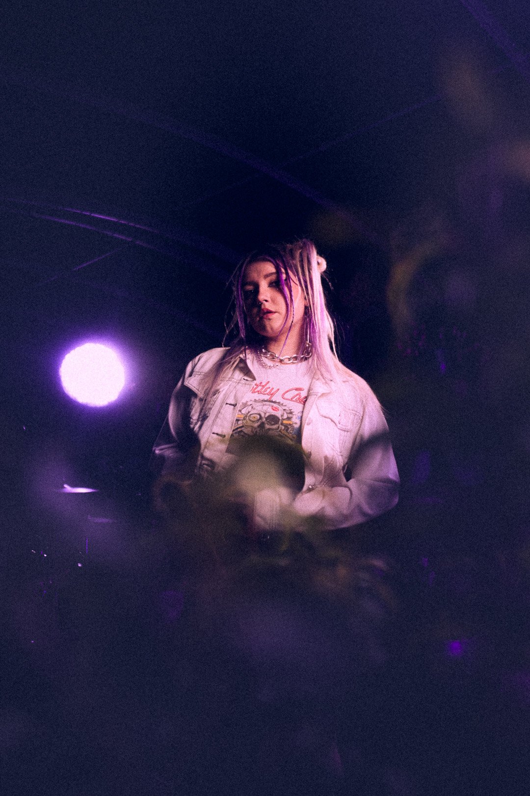 Ūla pausing under purple spotlight.