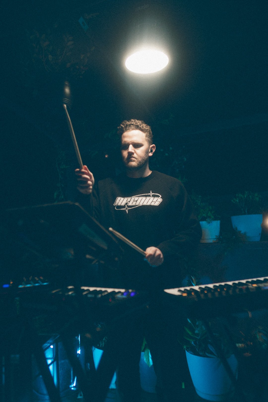 SAFIA drummer playing electronic percussion under overhead spotlight