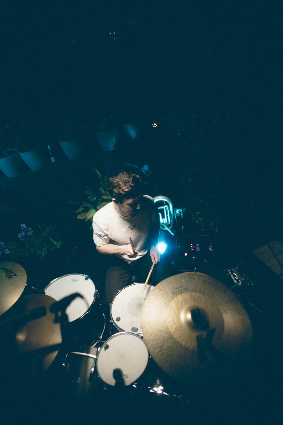 SAFIA drummer captured from above playing acoustic drums under cool blue lighting.