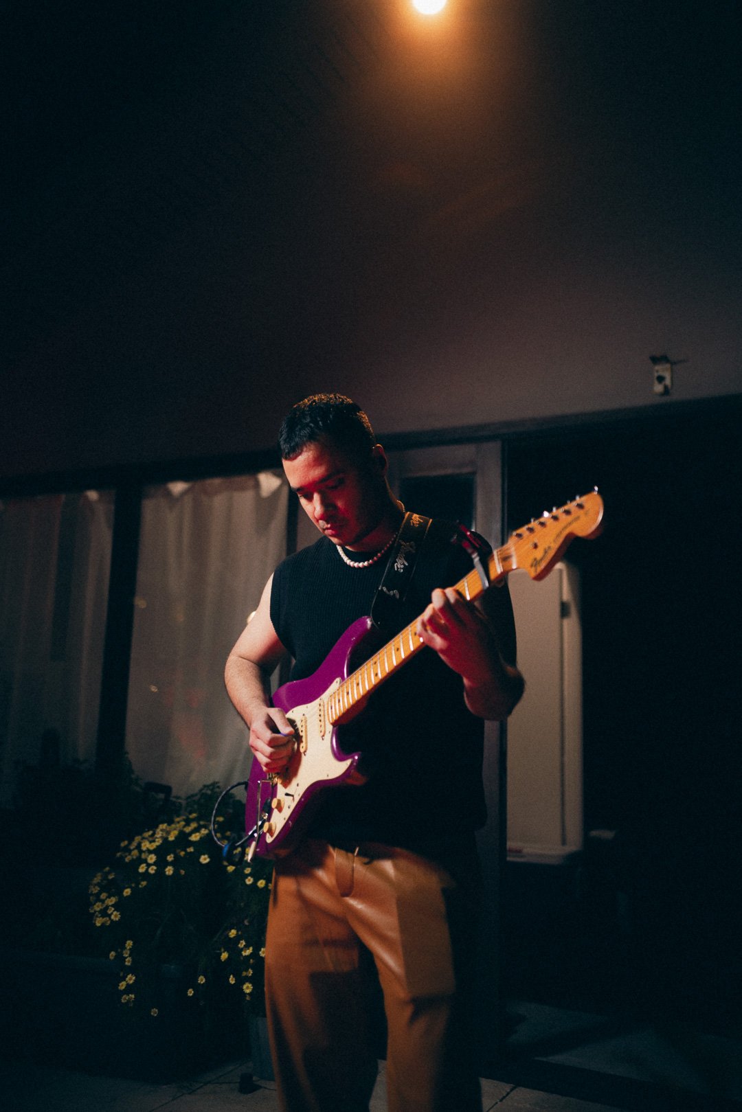 Guitarist playing electric guitar under warm rooftop lighting