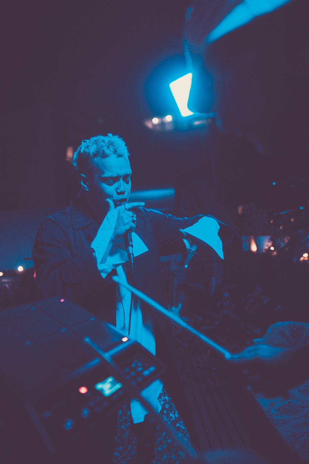 BOY SODA performing vocals under blue lighting on the Mood on the Roof stage.