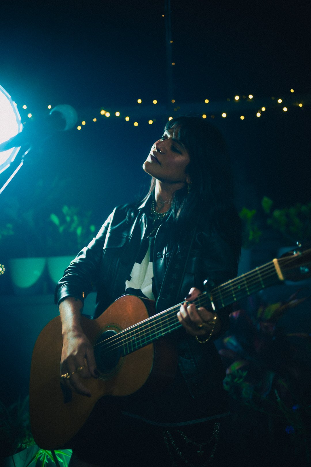 Guitarist tilting head back while strumming acoustic guitar mid-performance.