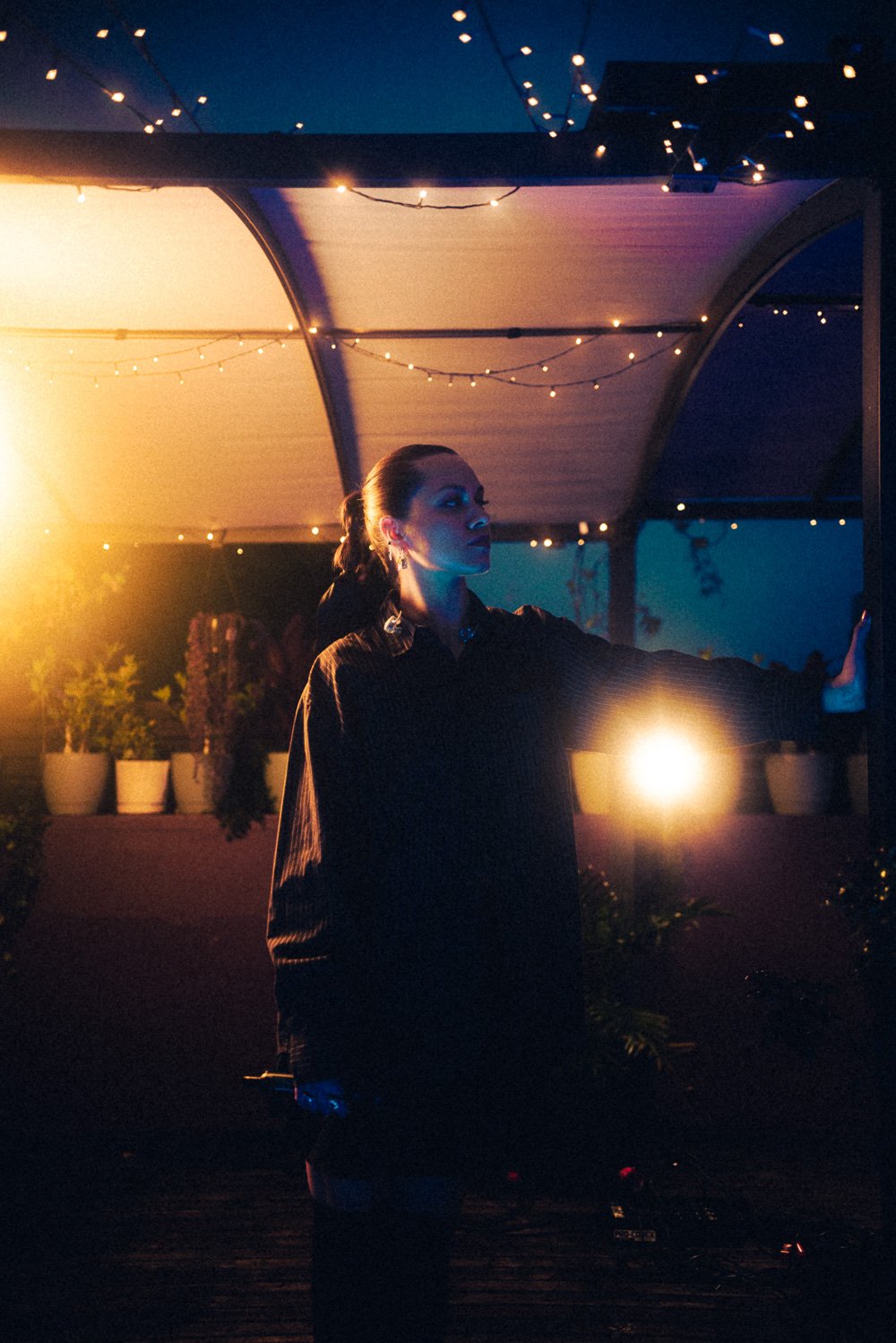 RIIKI REID performing solo under string lights on the Mood on the Roof rooftop