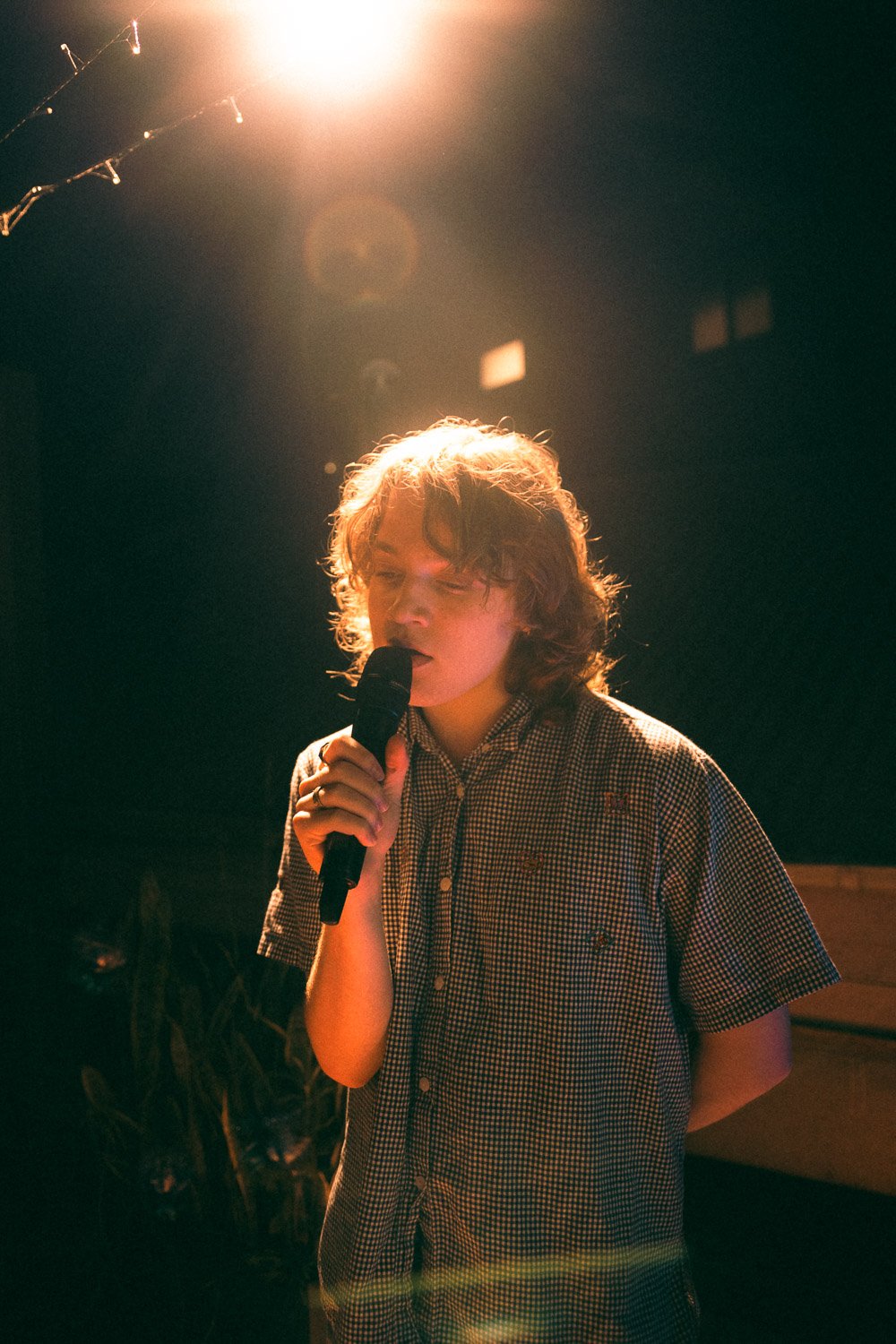 Caroline of Caroline & Claude singing into microphone under warm lights.