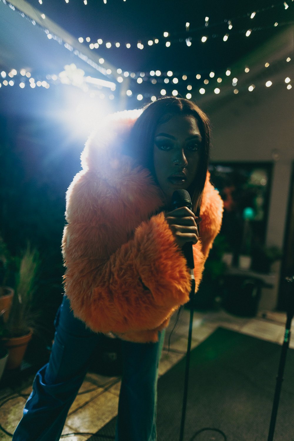 PANIA holding a microphone close to the camera during rooftop performance