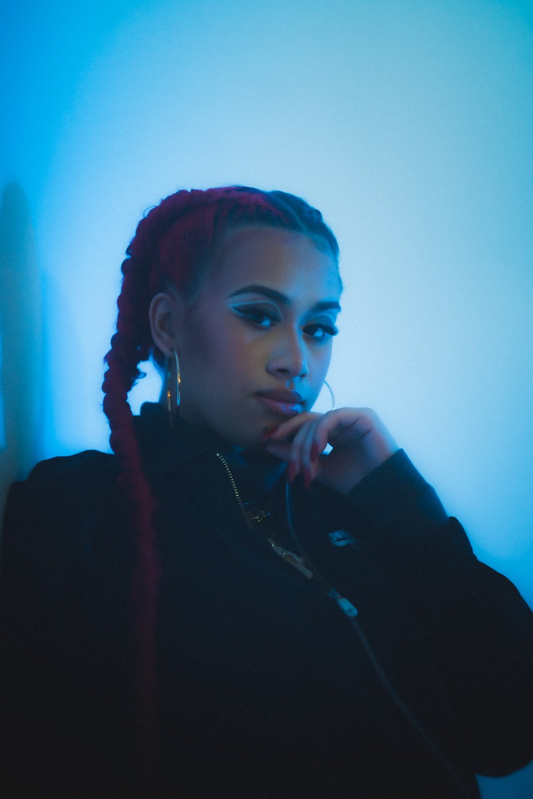 A.GIRL portrait with hand resting on chin under cool blue studio lighting
