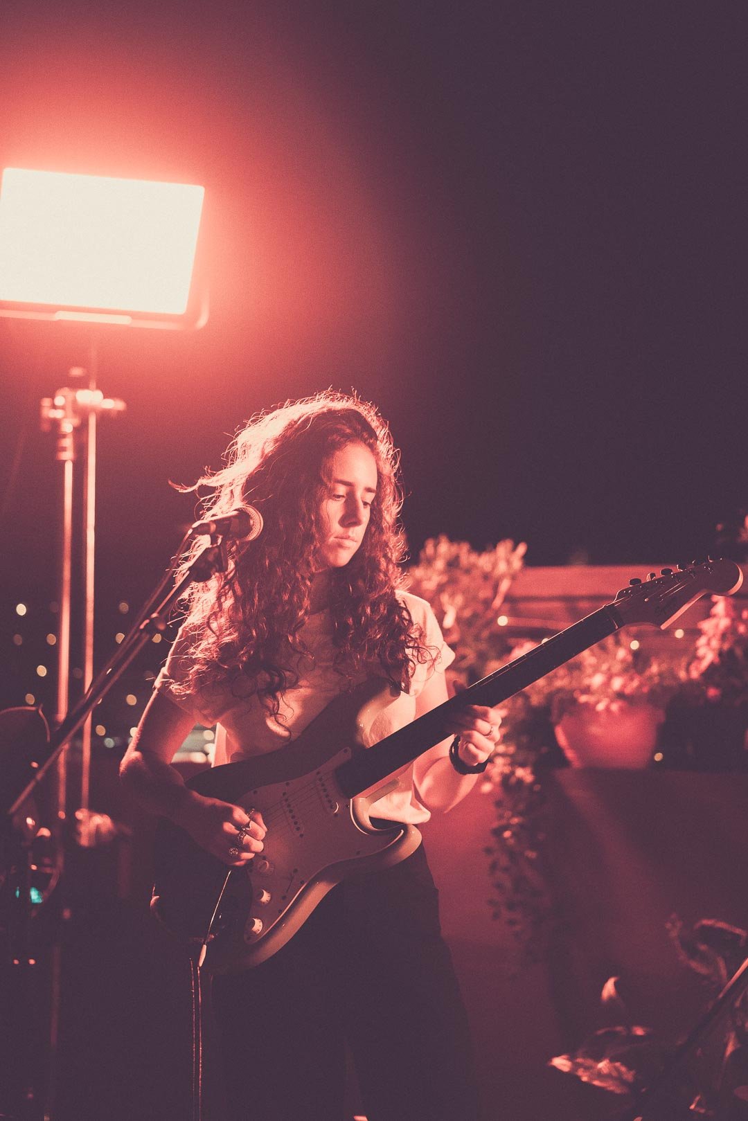 Guitarist concentrating on guitar parts mid-song on rooftop stage