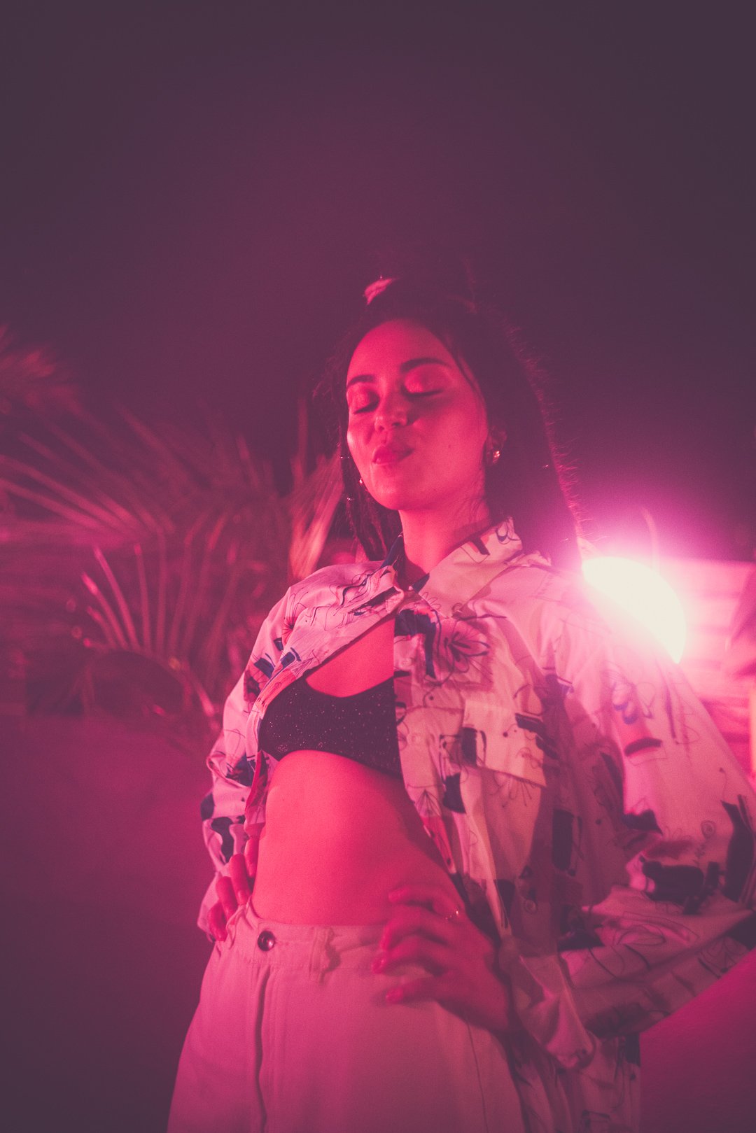 Rissa standing under pink lighting during Mood on the Roof rooftop set.