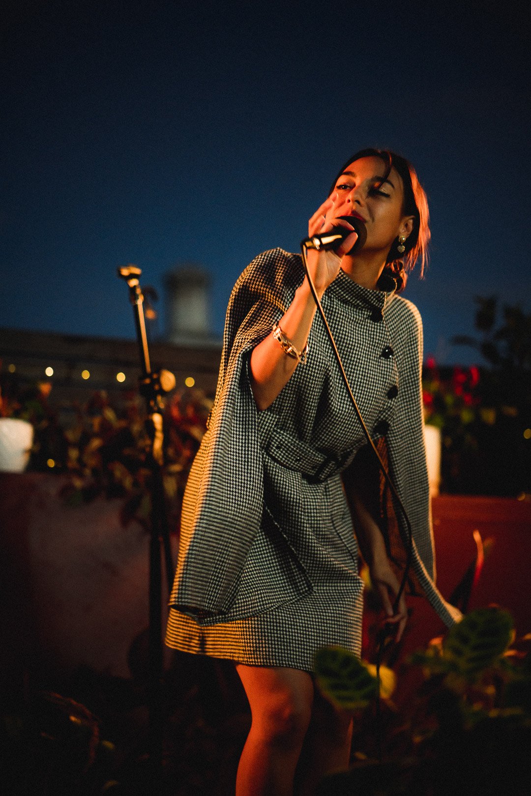 Telenova vocalist performing live on rooftop stage at night.