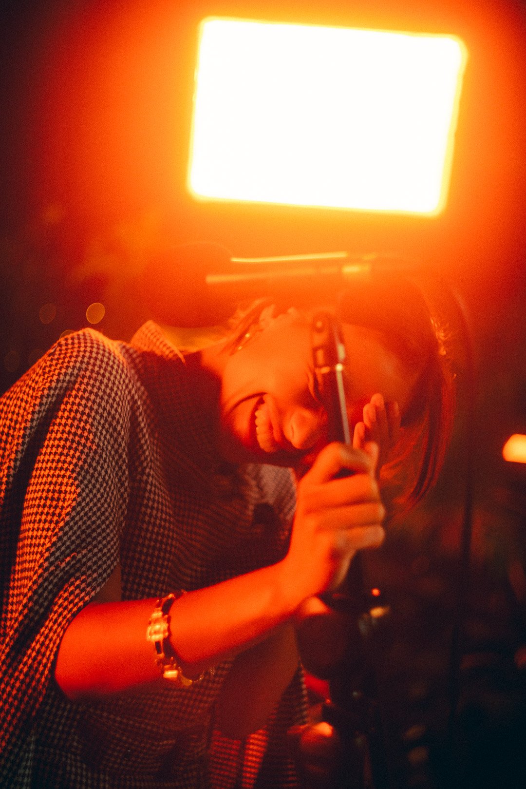 Telenova vocalist leaning toward microphone beneath warm rooftop lighting.