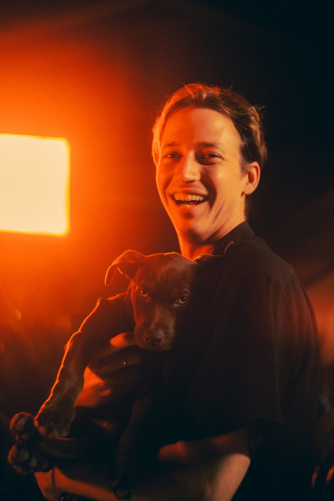 Edward Quinn of Telenova smiling while holding a small dog backstage.