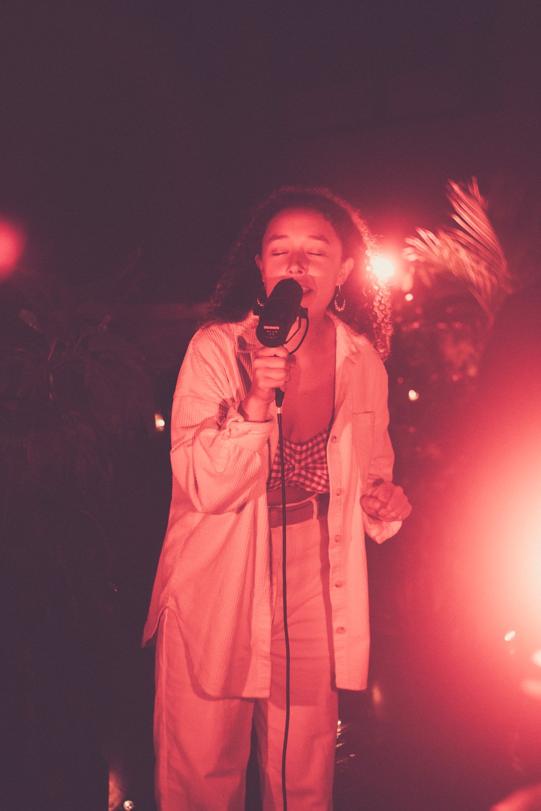 Ruby Jackson delivering soulful vocals into microphone under warm rooftop lighting