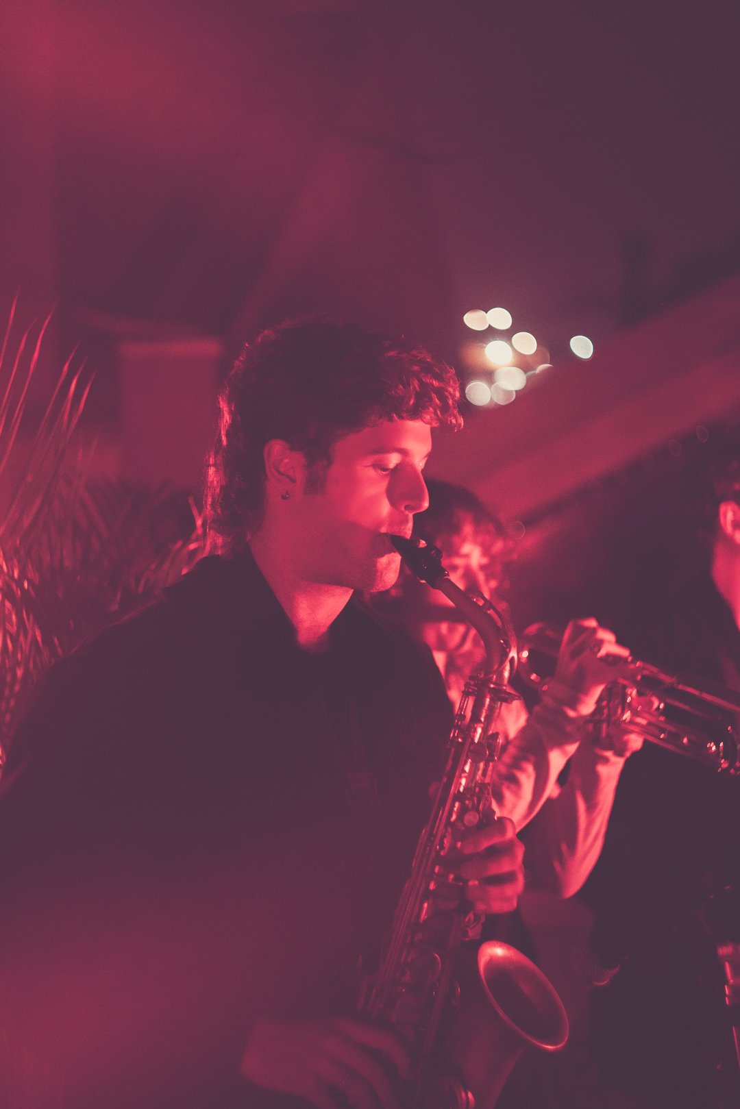 Saxophonist playing under red stage lights during Ruby Jackson live set.