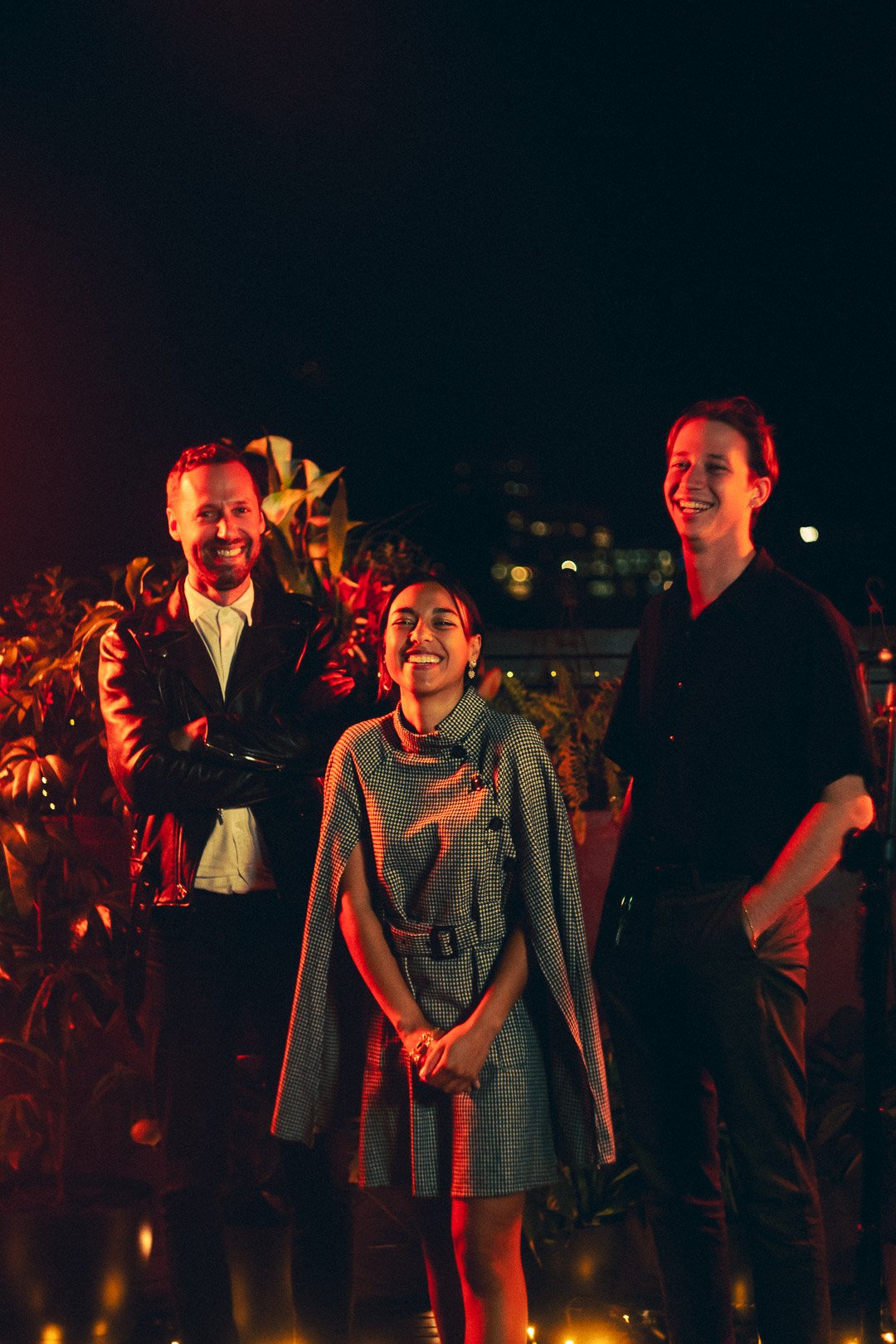 Telenova band standing together on rooftop under warm red lighting.