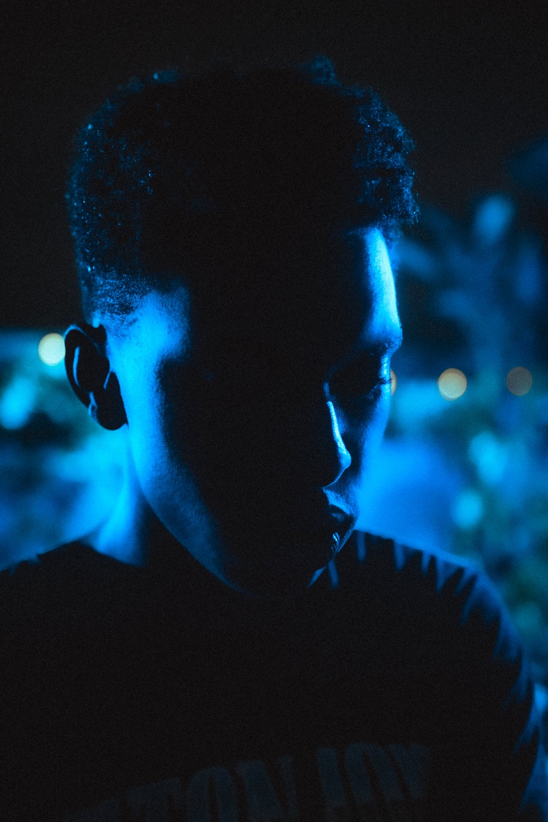 Close-up of Stevan looking downward under dramatic blue rooftop lighting.