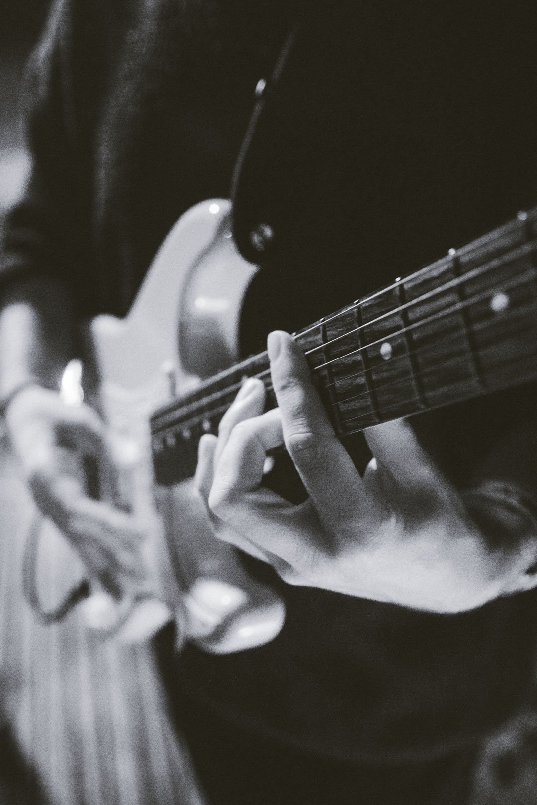 Close-up of hands playing electric guitar strings during a live rooftop performance.
