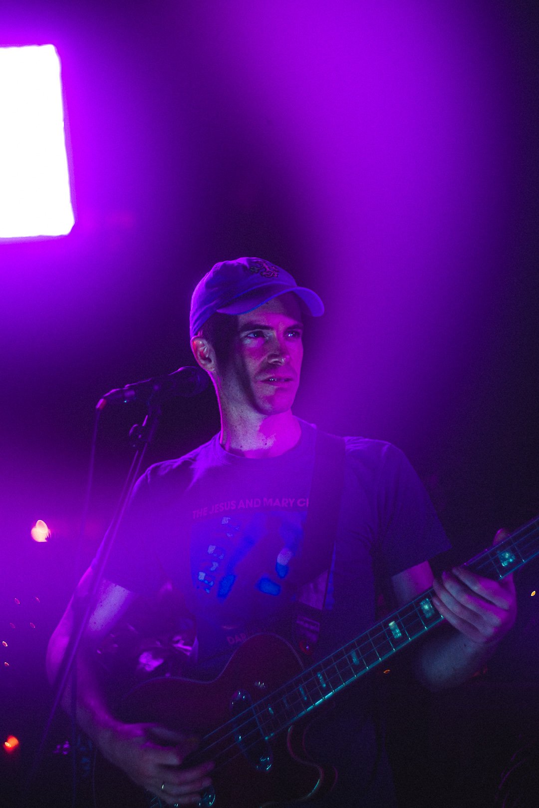 Live guitarist mid-song, bathed in purple haze lighting on the rooftop stage.
