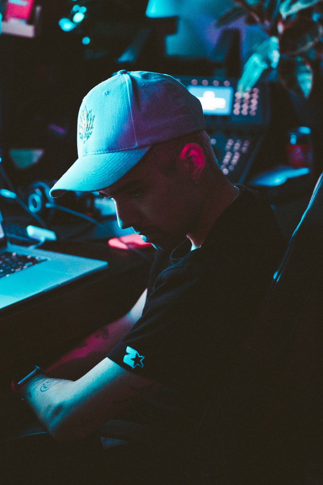 Producer adjusting equipment and laptop during a live rooftop music session.